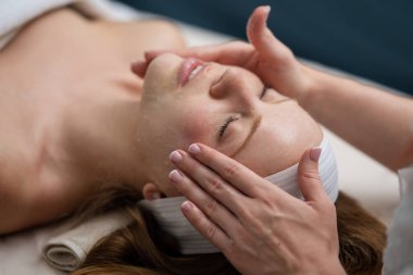Kozmetik uzmanı kadın müşteriler için spa ya da kuaförde canlandırıcı yüz işlemleri yapıyor. Kozmetoloji konsepti. Estetik kozmetoloji, yüz bakımı. SPA salonunda yüz gerdirme. Kozmetik prosedürü. Güzellik