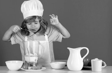 Yemek pişiren çocuklar. Aşçı çocuk sağlıklı yemek için taze sebze yapıyor. Mavi arka planda izole edilmiş küçük çocuk portresi. Aşçı çocuk. Yemek pişirme süreci