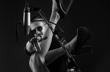 Seksi şarkıcı DJ bir müzik stüdyosunda mikrofonla rock şarkısı söylüyor.