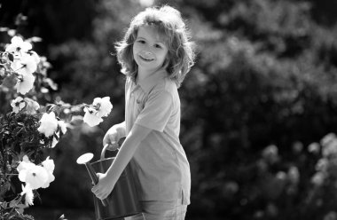 Çiçekleri sulama tenekesiyle sulayan şirin bir çocuk. Çocuk Bahçıvanlığı