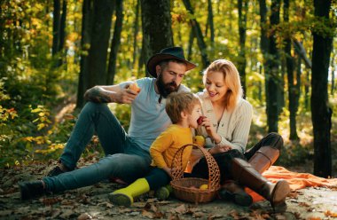 Anne baba ve küçük oğul pikniği. Doğada piknik. Köy ailesi. Mutlu aile anlamında. Doğayla bütünleşti. Aile günü konsepti. Çocuk ormanda yürürken dinlenirken mutlu bir aile..