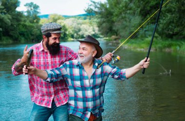 Genç adam ve yaşlı olgun adam balık avlamak. Man balıkçılık ve hobi tadını çıkarırken rahatlatıcı. Balıkçı -lık. Nehir rıhtımüzerinde olta çubukları ile Mutlu dedesi ve torunu