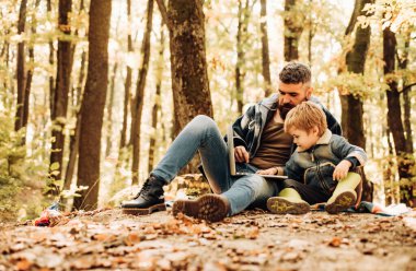 Sonbahar parkında baba ve çocuk oğlu eğleniyor ve gülüyor.