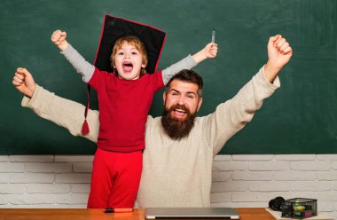 Yaşasın. Baba ve oğul yaşasın jesti ile sıkılmış yumruklar kaldırıyorlar. Baba oğluna okulda sınıfta ders veriyor. Evet iyi iş. Mutlu baba ve oğul tebeşir tahtası üzerinde. Baba ve oğul birlikte