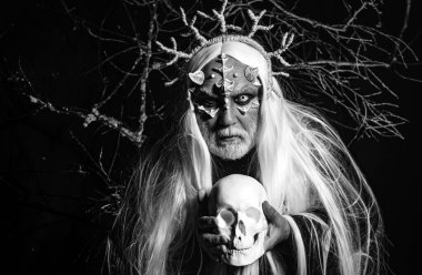 Man wizard with skull. Devil horror concept. Bearded old man dressed like Halloween monster. Man with a bull head. Vampire man with white eyes