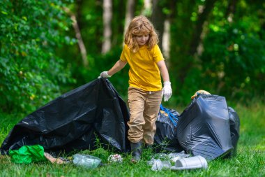 Çocuk doğayı temizlemek için plastik çöp topluyor. Çocuk dışarıdaki çöpleri temizliyor. Ekoloji konsepti. Çevre Günü. Dünyayı kurtar. Çöp geri dönüşüm çöpü. Ekoloji. Çevresel bakım. Eko çocuk