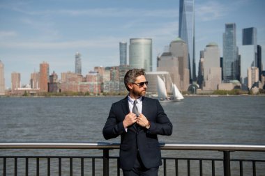 Kendine güvenen zengin iş adamı yöneticisi New York 'ta duruyor. İş dünyası Amerikan başarısı. Amerikan iş rüyası. Manhattan yakınlarında takım elbiseli Amerikalı işadamları. ABD 'de başarılı bir iş