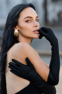 Sokakta poz veren güzel esmer kadın portresi. Moda dünyasından genç ve güzel bir kızın yakın plan kadın portresi, yaz sokak modası. Şık bir açık hava kadınının yüksek moda yakın plan portresi