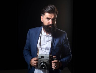 Kendine güvenen eski fotoğrafçı. Siyah arka planda izole edilmiş antika eski film kamerası olan ciddi bir erkek fotoğrafçının portresi.