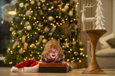 Evdeki noel ağacının yanındaki çocuk.