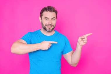 Uzayı işaret et. Mesafe uzak. Parmakla işaret eden mutlu yakışıklı adam, soyutlanmış pembe arka plan. Heyecanlı adam harika bir fikir işaret ediyor. Mavi tişörtlü adam parmağıyla işaret ediyor.