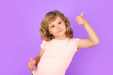 Child showing thumbs up on studio isolated background. Portrait of kid boy making thumbs up sign