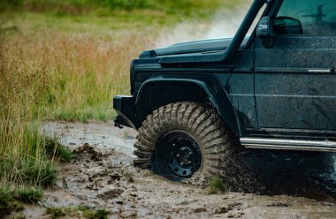 Çamur çukurundan çıkan bir arazi aracı. Off-road yarışında su sıçraması. Tekerlekleri ve toza dönüşen off-road 'u hareket ettir.