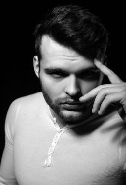 Genç adamın kameraya baktığı bir stüdyo fotoğrafı. Kendine güveni olan yakışıklı bir adam. Erkeklerin cinselliği, çekiciliği ve karizması, erkek güzelliği kavramı