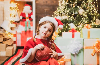 Noel Baba şapkalı mutlu çocuk Noel 'i kutlar. Noel çocukları. Noel çocuğu elinde kırmızı bir hediye kutusu tutuyor. Noel çocukları - mutluluk konsepti