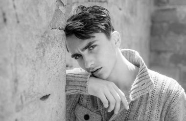 Gri duvarda duran yakışıklı gencin yakın portresi.