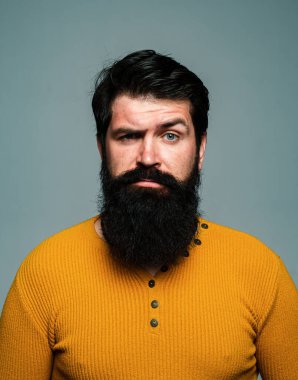 Ciddi bir adamın sakalı ve bıyığı var, ciddi görünüyor.