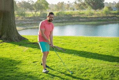 Golfçü akşam golf sahasında golf oynuyor. Güneşin altında golf oynayan bir adam.