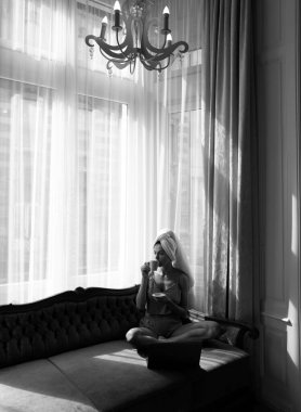 Genç ve çekici bir kadın kahve içiyor, evde dinleniyor. Sıcak, tembel bahar sabahı. Sabahları yatakta uyuduktan sonra güzel bir kız. Yatakta gevşeyen kadın manken uyanın.