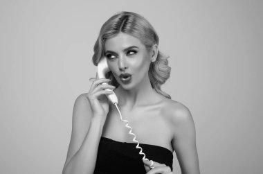 Retro telefonda konuşan bir kadının stüdyo portresi. Retro sabit hat telefonu. Sabit telefondan konuşan şehvetli genç bir kadın. Retro telefondan konuşan seksi kız. Kadın telefonu tut.