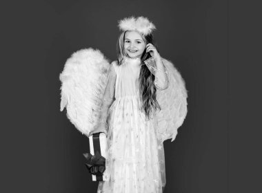 Hediyeli çocuk melek, stüdyo portresi. Beyaz kanatlı küçük melek hediyesini tutuyor. Neşeli melek gibi küçük kız. Sevgililer Günü