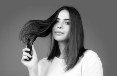 Sağlıklı ve parlak saçlarını tarayan genç bir kadın. Stüdyoda izole edilmiş. Güzellik saç bakımı