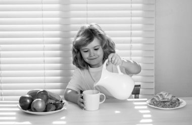 Sevimli çocuk inek sütü döküyor. Çocuk sağlıklı sebze yiyor. Süt, meyve ve sebzeli kahvaltı. Öğle ya da akşam yemeği sırasında çocuk yemek