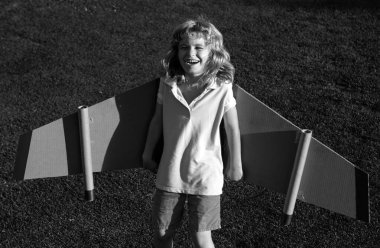 Uçakta uçan gülümseyen çocuk mukavva kanatlardan yapılmış. Rüya, hayal gücü, mutlu bir çocukluk. Seyahat ve yaz tatili konsepti