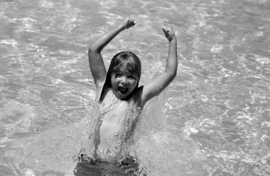 Excited amazed child splashing in swimming pool. Swim water sport activity on summer vacation with child