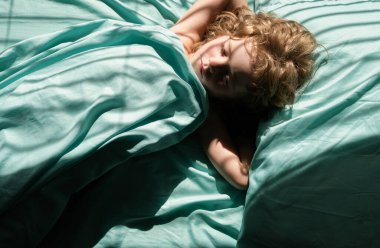 Kafkasyalı çocuk sabahları yatakta battaniyenin altında yastıkta uyuyor.