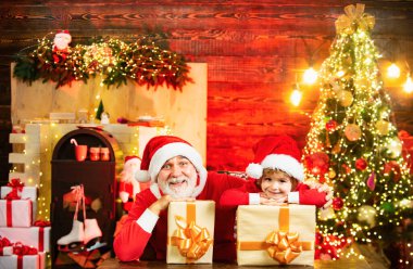 Hediyelerle dolu Noel Baba çocuk. Noel ve Yeni Yıl posterleri için. Sevimli çocuk ve büyükbaba evde Noel Baba 'yı oynuyor.