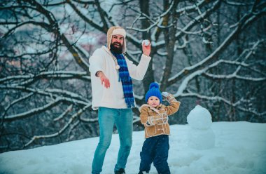 Baba ve oğlu dışarıda oynuyorlar. Sevimli küçük çocuk çocuk ve karlı alanda mutlu baba açık. Soğuk kış parkıkış ailesi. Noel tatili