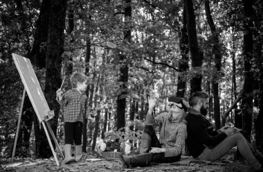 İş ve mesleki meslek. Küçük oğlum doğayı resmediyor. Sanat ve kendini ifade etme. Yetenek geliştirme. Resim becerileri. Anne ve baba çocuk resim yaparken parkta çalışıyor. Dinlenme ve hobi kavramı.