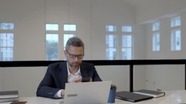 İş adamı ofiste telefonla konuşuyor. Çalışan telefonda konuşuyordu. Telefon görüşmesi. Telefon kullanan bir iş adamı. CEO akıllı telefondan sohbet ediyor. İş konuşmaları. Akıllı telefondan sorunları çözen adam