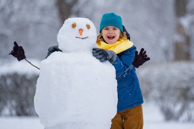 Mutlu Çocuk kışın kardan adam için kartopu yapıyor. Çocuk karda oynuyor. Açık havada aktif kış oyunları. Çocuk karla oynarken eğleniyor. Çocuklar için açık havada kış tatili. Güneşli kış gününde çocuk oyunu