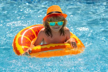 Çocuk havuzda dinleniyor. Çocuk su havuzunda yüzüyor. Yaz çocuk aktiviteleri, su sporları
