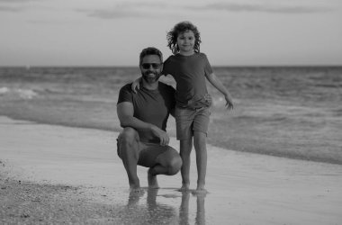 Baba oğul kucaklaşması sahili. Yaz tatili. Baba ve oğul birlikte yaz tatilinin tadını çıkarıyorlar. Baba oğul sahilde oynuyorlar. Arkadaş canlısı bir aile. Baba ve oğul denizde vakit geçiriyorlar.