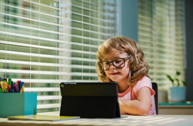 Sanal sınıftaki çocuk. Evde okul var. Evde eğitim gören küçük bir çocuk uzak bir toplantıda öğretmeniyle çevrimiçi sınıfta öğreniyor.