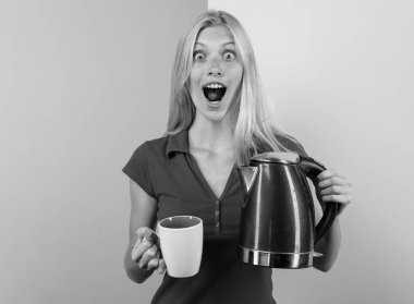 Sıcak içecek. Heyecanlı genç bayan ev hanımı çay ve çaydanlığı renk stüdyosunun arka planında çay ya da kahve olarak kullanıp çay yapıyor. Elektrikli su ısıtıcısı kullanan komik kız.