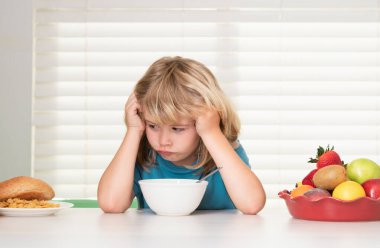 İştahsız bir çocuğun portresi. İştah kaybı kavramı. Çocuk öğle yemeği sırasında mutfakta sebze ve meyve yiyen ergen bir çocuk. Sağlıklı yemek, sebze yemeği...