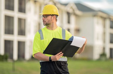 Dosyası olan mühendis, bina teftişi. İnşaat alanında çalışan bir inşaat işçisi. İnşaat alanında miğferi olan bir buider. İnşaat alanında çalışan bir işçi. Bilder in hardhat