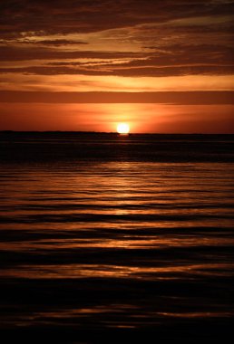 Altın gökyüzü ve deniz suyu. Deniz yüzeyinin altında büyük sarı güneşli bir gün batımı. Sakin okyanus, gün batımında gökyüzü ve bulutların arasında güneş. Sakin okyanus ve gökyüzü arka planı