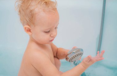 Küvetteki bebek. Mutlu yürümeye başlayan bebek anne ve köpük ile oynarken bir banyo alarak. Çocuk bebek beyaz küvette banyo