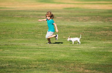 Mutlu çocuk dışarıda bir köpekle koşuyor.