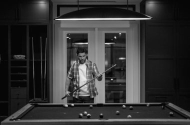 Bilardo oynayan bir adam. Adam bilardo odasında Amerikan bilardosu oynuyor. Bilardo oyuncusu. Bilardo kulübünde bilardo oynayan genç bir profesyonel.