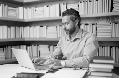 Kütüphanede kitabı olan bir öğretmenin portresi. Üniversitede yakışıklı bir öğretmen. Öğretmenler Günü. İyi bir öğretmen. Üniversitede öğretmen. Kütüphanede kitapları olan bir adam. Bilgi ve eğitim kavramı