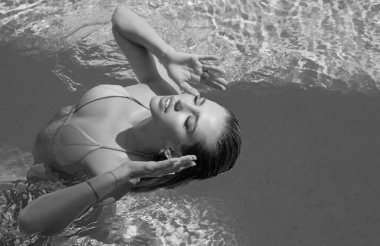 Beautiful woman in swimwear relaxing in swimming pool. Portrait of woman in bikini in water. Relaxed girl in swim pool. Young girl at pool side. Enjoy life, summer vacations, holidays, sunbathing and