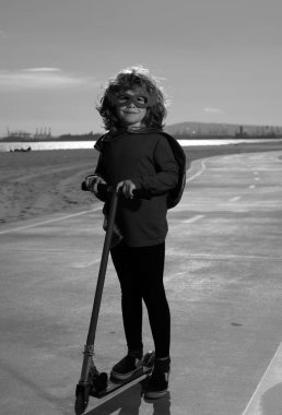 Küçük çocuk süper kahramanı oynuyor. Erkek süper kahraman konsepti. Parkta motosikletli bir çocuk. Çocuklar paten kaymayı öğrenirler.