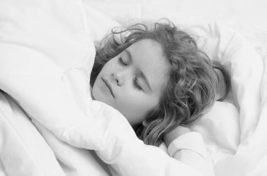 Little kid sleeps on bed, napping. Cute child sleeping. Comfortable bed, soft pillow orthopedic mattress