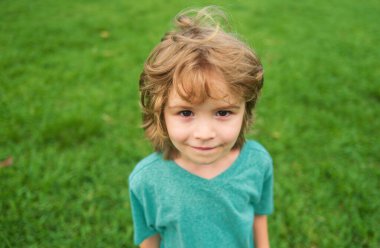 Yakından, çekici, gülen çocuk. Çocuk duyguları konsepti. Açık havada gülümseyen genç bir çocuğun portresi. Çimen arkaplanı